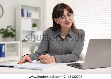 Smiling secretary doing paperwork at table in office