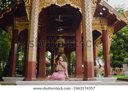 South Asian model in Thai costume sitting inside a Buddhist temple landmark in Chiang Mai