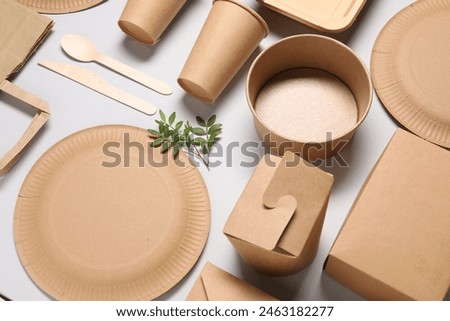 Eco friendly food packaging. Paper containers, tableware and green twigs on light grey background