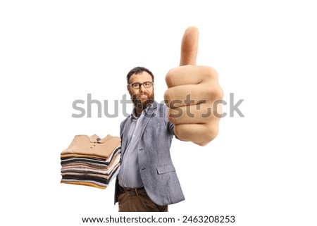 Man holding a pile of folded clothes and showing thumbs up isolated on a white background