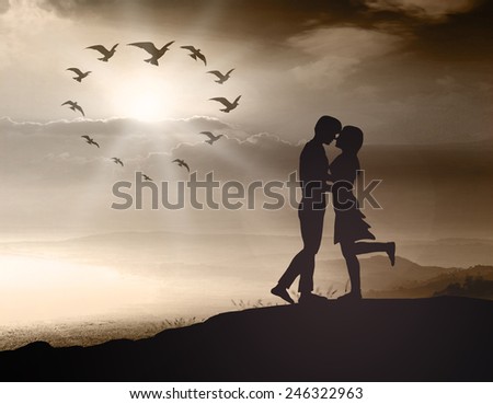 Silhouette couple over blurred sunset background.