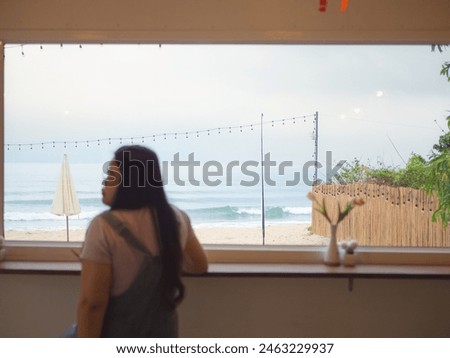 View sea seen through cafe with blurred rear view of woman relaxing on bar, Blur object.