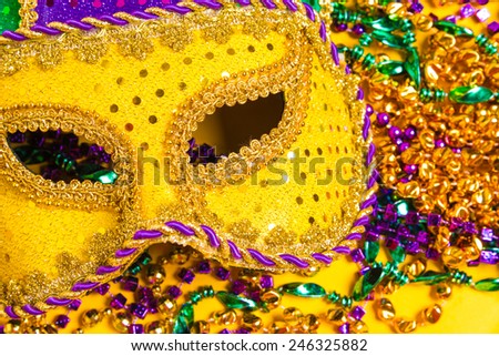 Assorted colorful Mardi Gras mask on yellow background with beads
