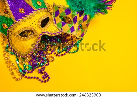 Assorted colorful Mardi Gras mask on yellow background with beads