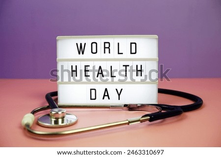World Health Day letterboard text on LED Lightbox and stethoscope on pink and purple background