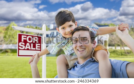 Mixed Race Father and Son Celebrating with a Piggyback in Front Their House and For Sale Real Estate Sign.