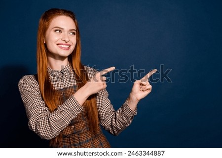 Photo of cheerful dreamy lady lady dressed plaid outfit looking pointing two fingers empty space isolated dark blue color background