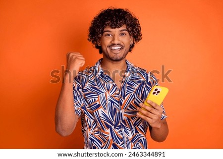 Photo portrait of handsome young man device winning dressed stylish colorful garment isolated on orange color background
