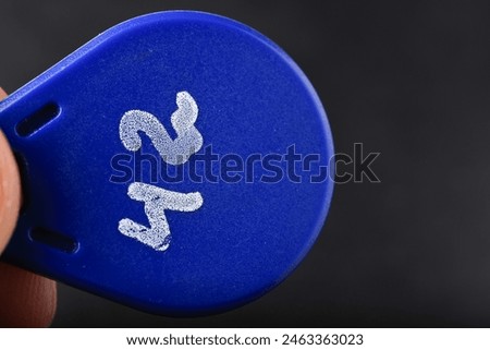 A blue object with the number 23 on it. The object is being held by a person, magnetic key for intercom