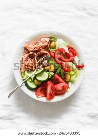 Delicious balanced lunch - grilled salmon, boiled egg, fresh vegetable salad on a light background, top view