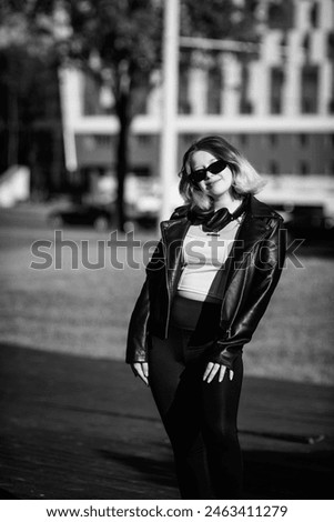 Portrait of a young short-haired girl in a leather jacket outdoors. Black and white photo.