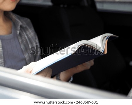 Young woman reads a book in the car while parked