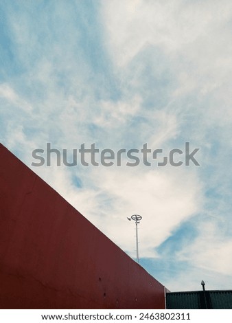 composition of red wall layout with tower dan cloudy blue sky as the background