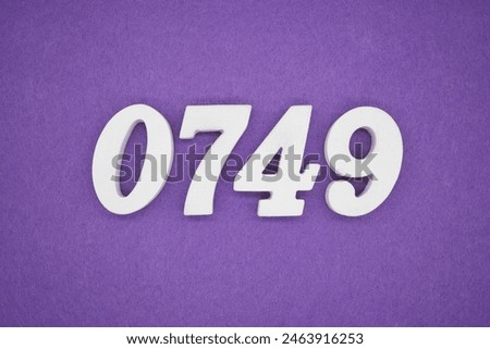 The number 0749 is made from white painted wood. Place it on a purple paper background.