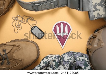 Badge of Ukrainian army with trident, tag and military equipment on beige background