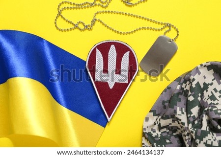 Badge with trident, tag, military hat and flag of Ukraine on yellow background