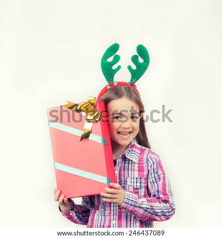 Happy baby girl wearing reindeer horns with a Christmas gift, isolated on white.