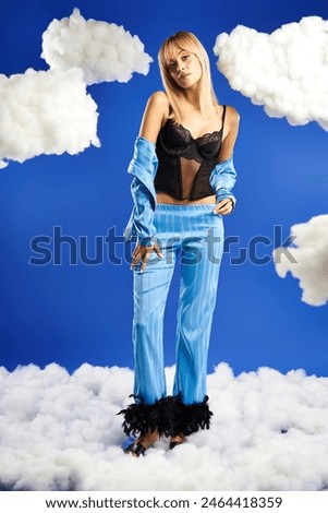 A vibrant blonde woman in bustier dances gracefully among fluffy clouds in a blue sky.