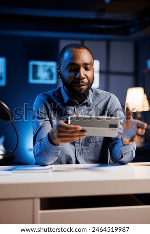 African american entertainer doing technology review of Bluetooth portable speaker for online streaming channel. BIPOC influencer films music playing device unboxing for niche audience Royalty-Free Stock Photo #2464519987