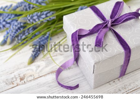 Gift box with violet ribbon and bouquet of hyacinth on wooden background