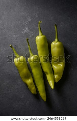 banana peppers on black textured background, long curved shape with mild heat and tangy sweet flavored popular chili pepper dark moody food photography with copy space Royalty-Free Stock Photo #2464559269