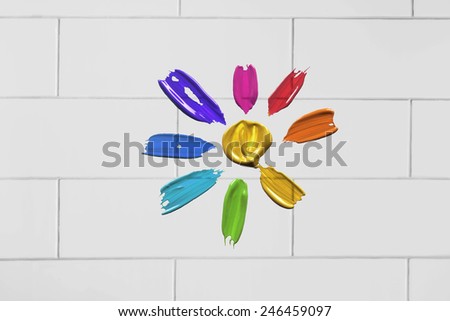 Painted multicolor flower on white brick wall as a background