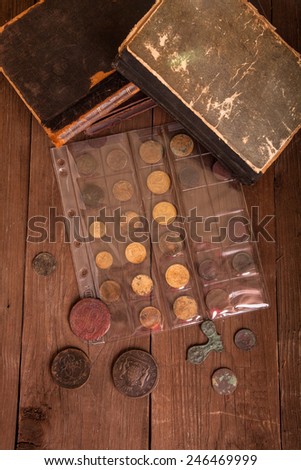 Vintage books and coins on old wooden table.