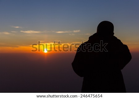 photographer taking picture of landscape during sunrise.