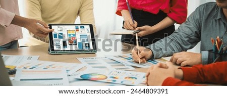 Cropped image of interior designer team chooses color from color swatches while tablet displayed UI and UX designs for mobiles app and website. Creative design and business concept. Variegated.