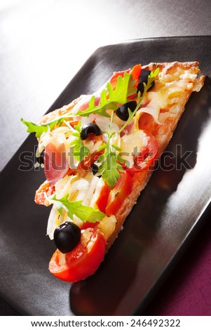Delicious hot pizza piece triangle on black plate on table, minimal contemporary style. 