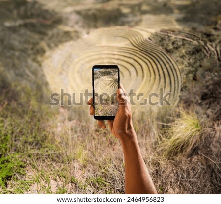 Unrecognizable person of a latin person holding a cell phone at the archaeological site of Moray in Cusco, Peru.