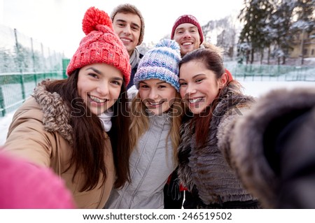 people, friendship, technology, winter and leisure concept - happy friends taking selfie with smartphone or camera outdoors