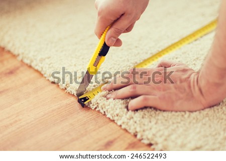 repair, building and home concept - close up of male hands cutting carpet with blade Royalty-Free Stock Photo #246522493