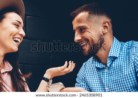 Cheerful male and female friends enjoying free time together joking and share multimedia in networks during meeting in cafe, romantic couple laughing viewing funny photos on mobile phone during date
