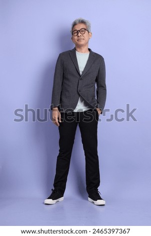 50s asian senior Businessman with glasses dressed in formal outfit with gesture of standing isolated on purple background. 
