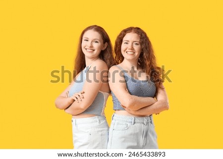 Happy redhead sisters on yellow background
