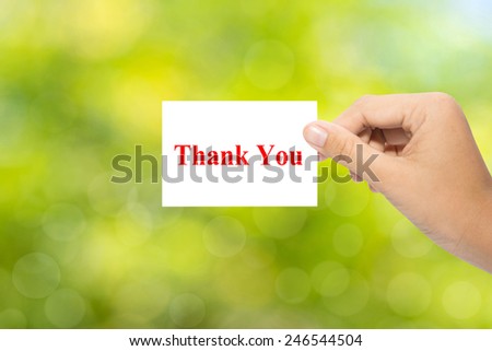 Hand holding a paper Thank You on green background 