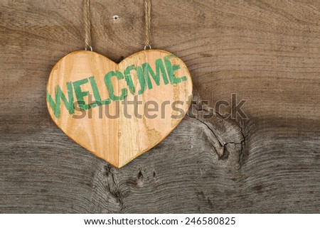 Welcome message wooden heart sign from recycled old palette on rough grey wooden background, copy space