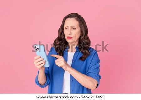 Photo portrait of nice pensioner female hold device nervous bad news wear trendy blue outfit isolated on pink color background
