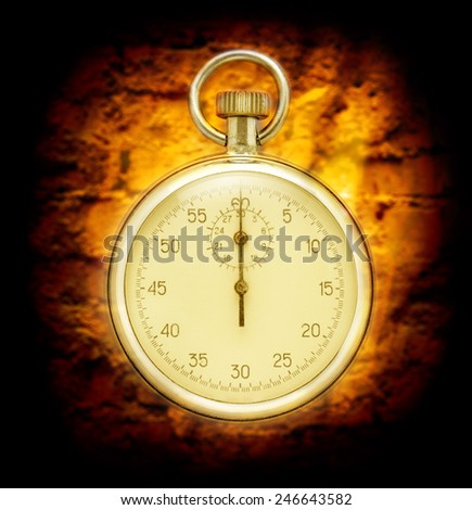 Stopwatch on cracked wall background in yellow toning