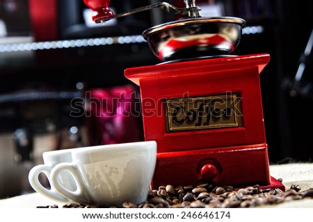 Picture of coffee cups in front of manual coffee grinder