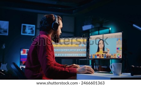 Photographer using photo editing software on PC display in multimedia creative studio while listening to music. Freelancer using photographs retouching program, hearing songs through headphones