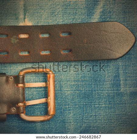 Vintage leather belt with a buckle on the background of denim. instagram image style