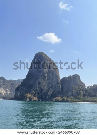 a photography of a boat traveling past a mountain in the ocean.