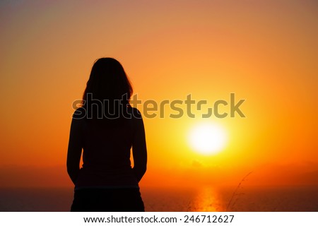 woman silhouette by the shore at sunset