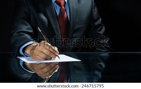 Close up of businessman sitting at table and signing document