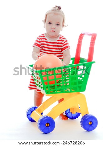 The little girl puts a great ball into the toy truck.Isolated on white background