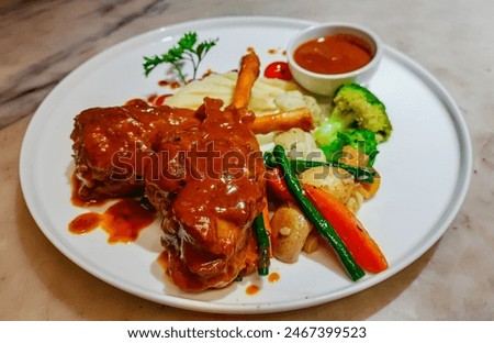Braised lamb shank in restaurant. Modern style traditional braised slow cooked lamb shank in red wine sauce with shallots and mashed potatoes offered as top view with copy space.