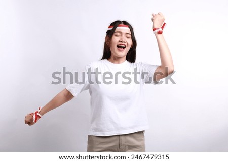 A young Asian woman with a happy successful expression wearing white shirt and red white flag ribbon isolated by white background