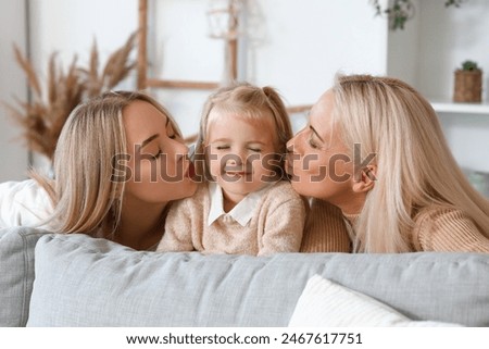 Cute little girl with her mother and granny kissing at home